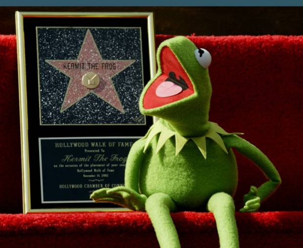The most popular Muppet, Kermit the Frog, poses with his plaque in Hollywood after Kermit received his own star on the Hollywood Walk of Fame in this November 14, 2002 file photo. Embattled Disney Chief Executive and Chairman Michael Eisner on February 17, 2004 announced a deal to buy Kermit and the rest of the fabled Muppets franchise from Jim Henson Co., concluding a courtship that had lasted more than a decade. The announcement of the Muppets deal and plans for a new Disney television show featuring the familiar characters seemed timed to underscore that point in the face of Comcast Corp's $49-billion all-stock takeover offer. REUTERS/Fred Prouser