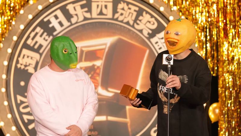 微笑橘子頭套(右)由去年奪下「拔得頭醜獎」的綠魚頭套手中領到講座。