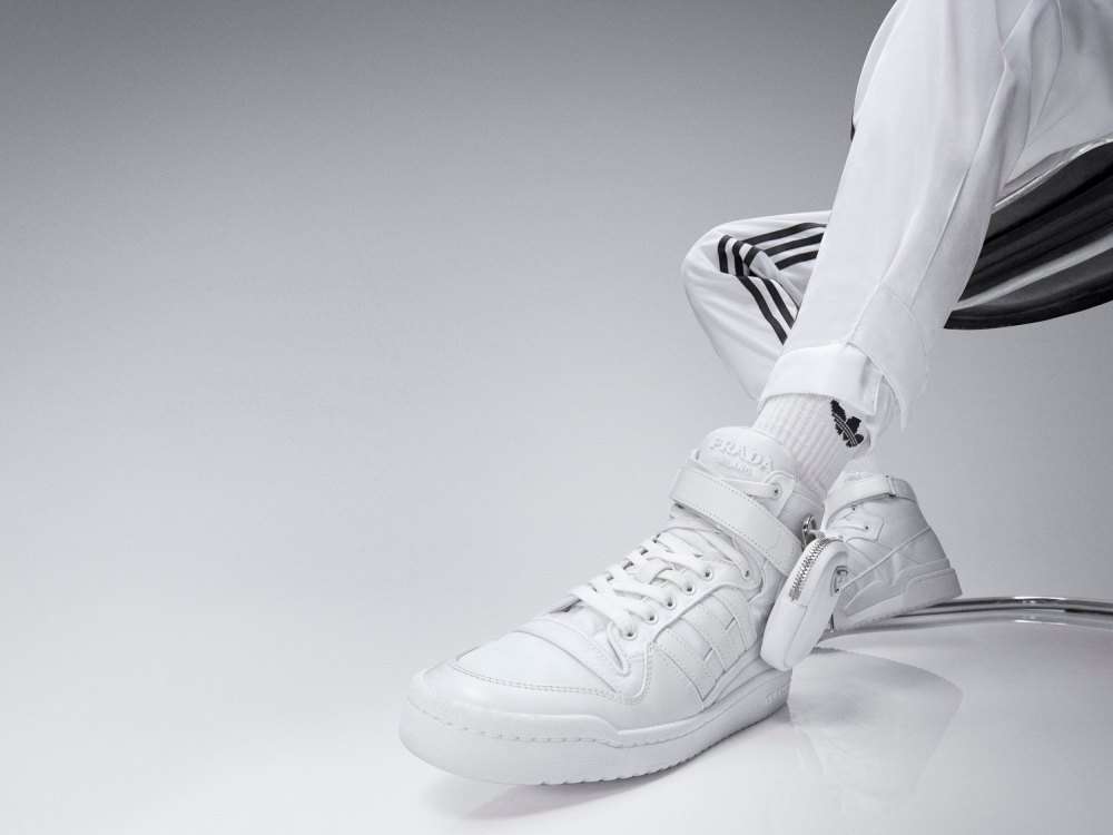 以Prada 的工藝美學重新設計adidas Originals 的傳奇經典 Forum 鞋款，融入 Prada 招牌的 Re-Nylon 再生尼龍材質，並透過對 adidas 深入的研究與探討，在精緻的工藝技術和運動風格中取得完美平衡。鞋面以 Prada 的 Re-Nylon 再生尼龍面料在結構上重新升級，外觀上保留 Forum 鞋款的功能性和美學特徵，加上極具辨識度的可拆卸Prada 迷你小包配件，上面綴有標誌性琺瑯金屬三角 Logo。鞋側面的三線與鞋頭以奢華的皮革拼接覆蓋，突顯 Prada 舉世聞名的皮革製作工藝，展現優雅時尚與前衛顛覆並具風格。